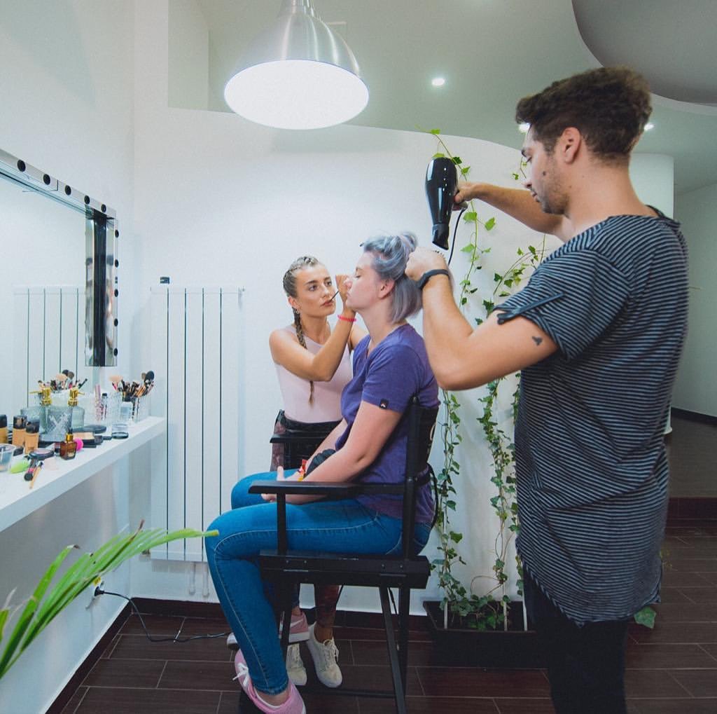Liviu coafează păr lilac în salonul Factory, alături de un make-up artist
